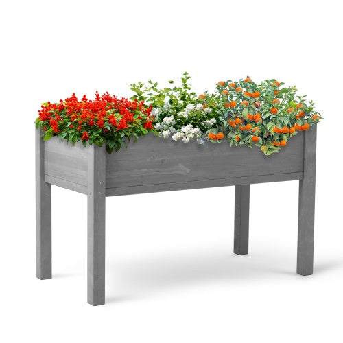 Elevated grey wooden garden bed with blooming outdoor plants.