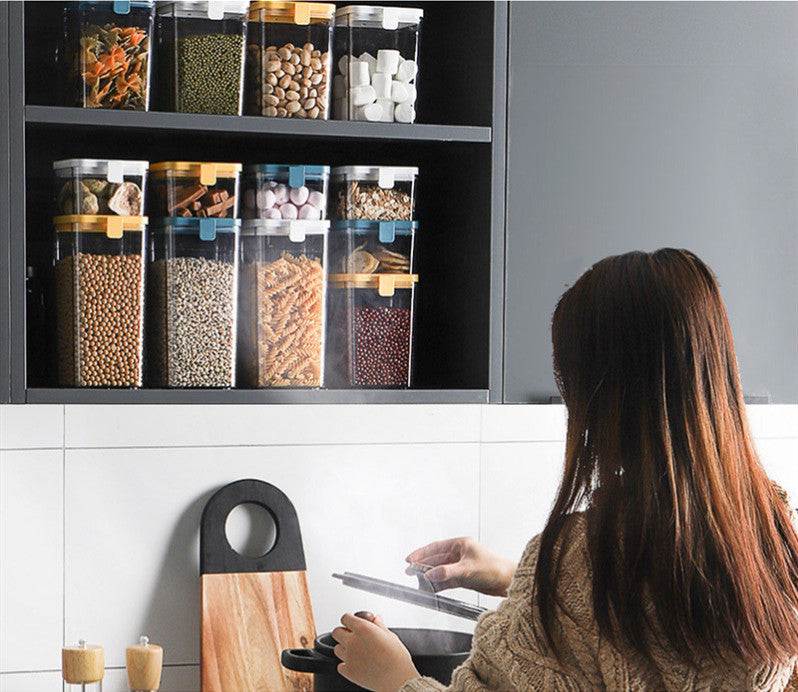 Modern kitchen with sealed storage jars in cupboard, woman cooking with tablet.
