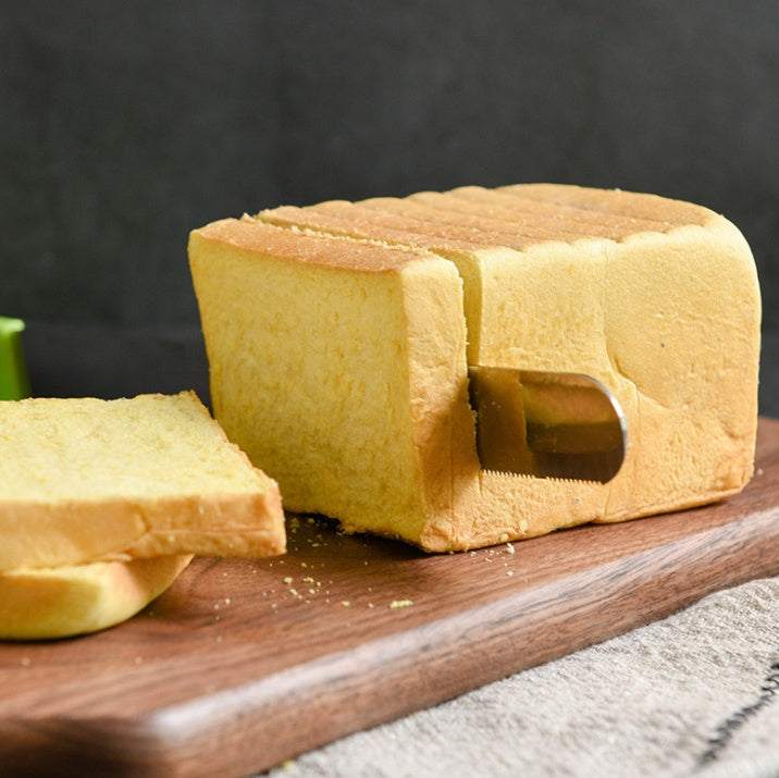 Bakerdream stainless steel serrated bread knife slicing through bread on wooden board.