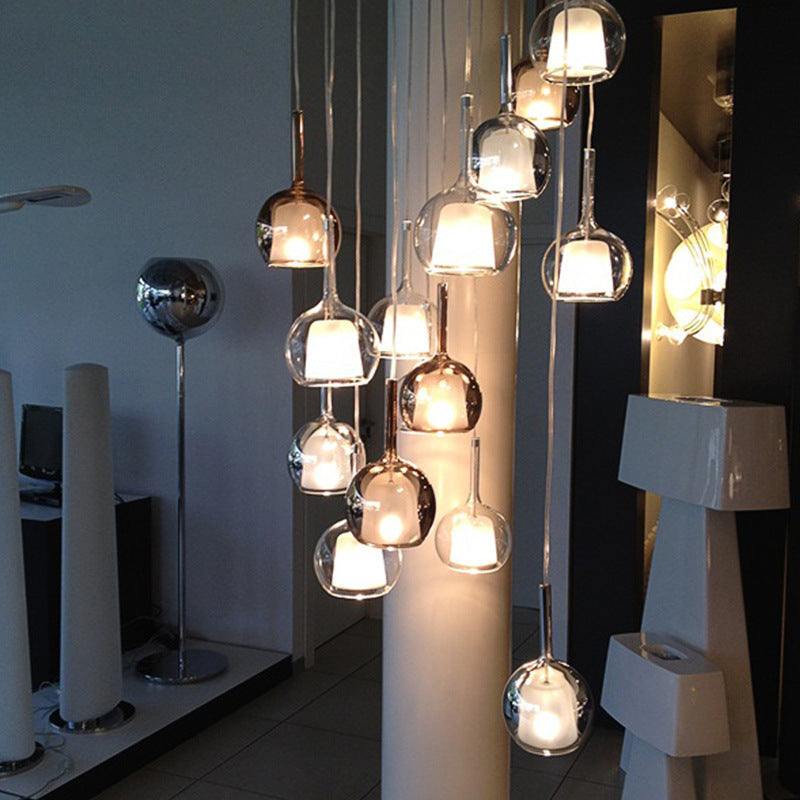 Nordic Creative Staircase Long Chandelier with glass spheres illuminating a modern space.