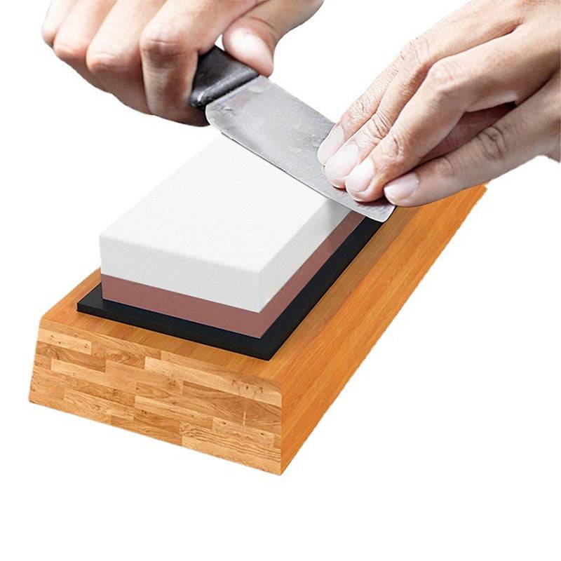Home kitchen whetstone with bamboo base, sharpening a knife.
