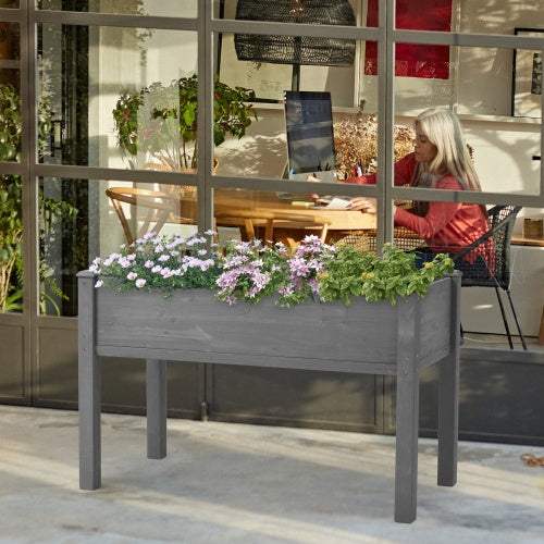 Elevated garden bed with legs and flowers placed outdoors.