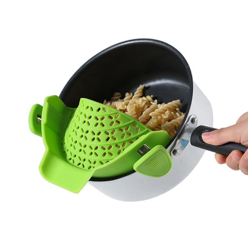 Green silicone pot side drain stopper attached to cooking pot with pasta, modern kitchen gadget.