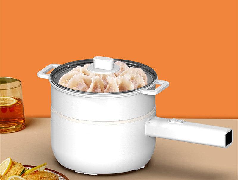 Multifunctional electric cooker with non-stick pot steaming dumplings on a countertop.