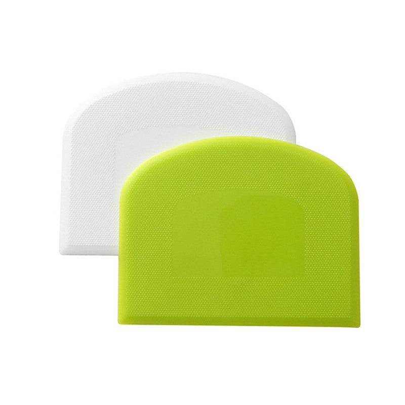 Green and white plastic kitchen scrapers for cutting flour and cake cream.