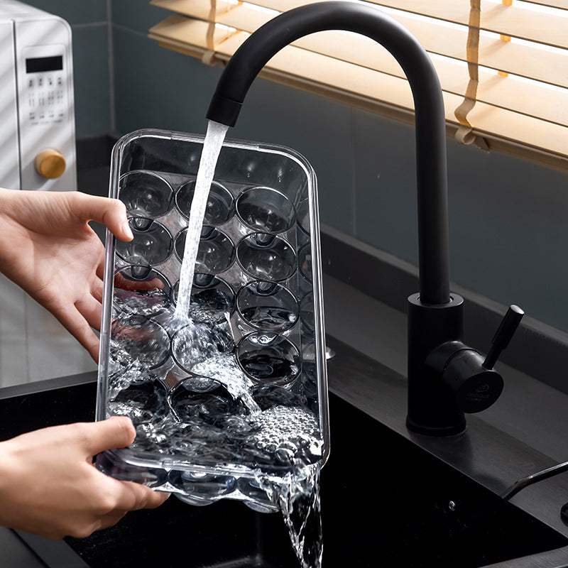 PET kitchen organizer being washed under a faucet, featuring a sealed storage box with lid.