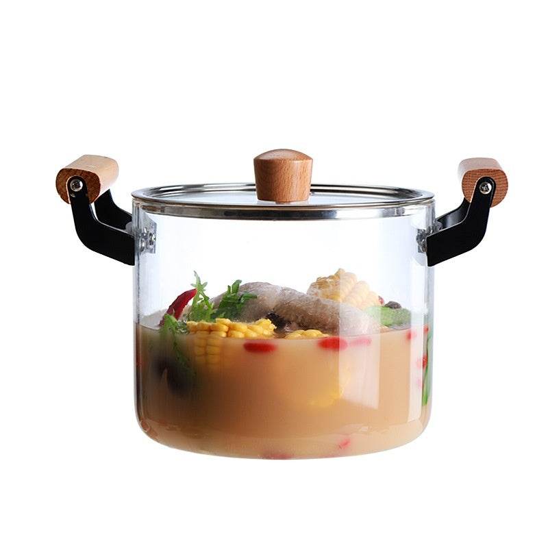 Borosilicate Visions Cookware Pot with wooden handles filled with soup and vegetables.