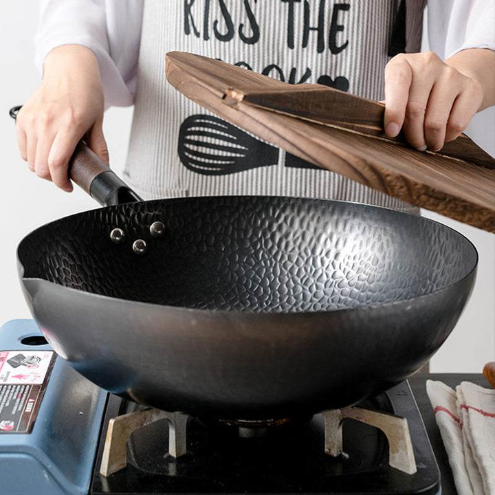 Iron pan traditional iron wok with wooden handle on stove.