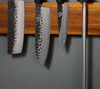 Wall-mounted solid wood magnetic knife rack holding kitchen knives.