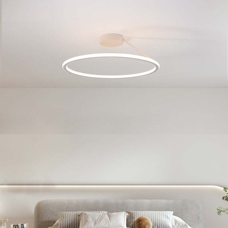 Simple modern LED ceiling light in round design above a bed in a room.