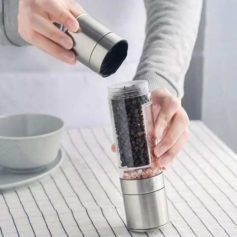 Manual stainless steel salt and pepper grinder in use, showcasing dual compartments and adjustable ceramic grinding mechanism.