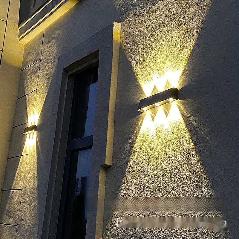 Solar outdoor wall lamp illuminating a courtyard with warm white light.