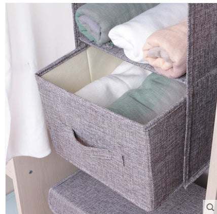 Hanging cotton cloth drawer storage in closet with folded clothes.